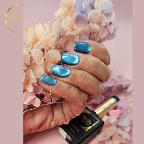 Close-up van een hand met korte nagels gelakt in een blauwe cateye gellak, waarbij het magnetische cat-eye effect zichtbaar is als een zachte lichtreflectie die diepte en glans geeft aan de kleur.