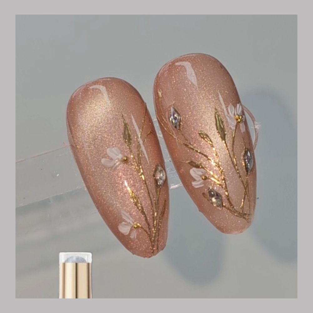 2 amandel vormige nailart tips met cateye Coral Reef en goudkleurige nailart bloemen.