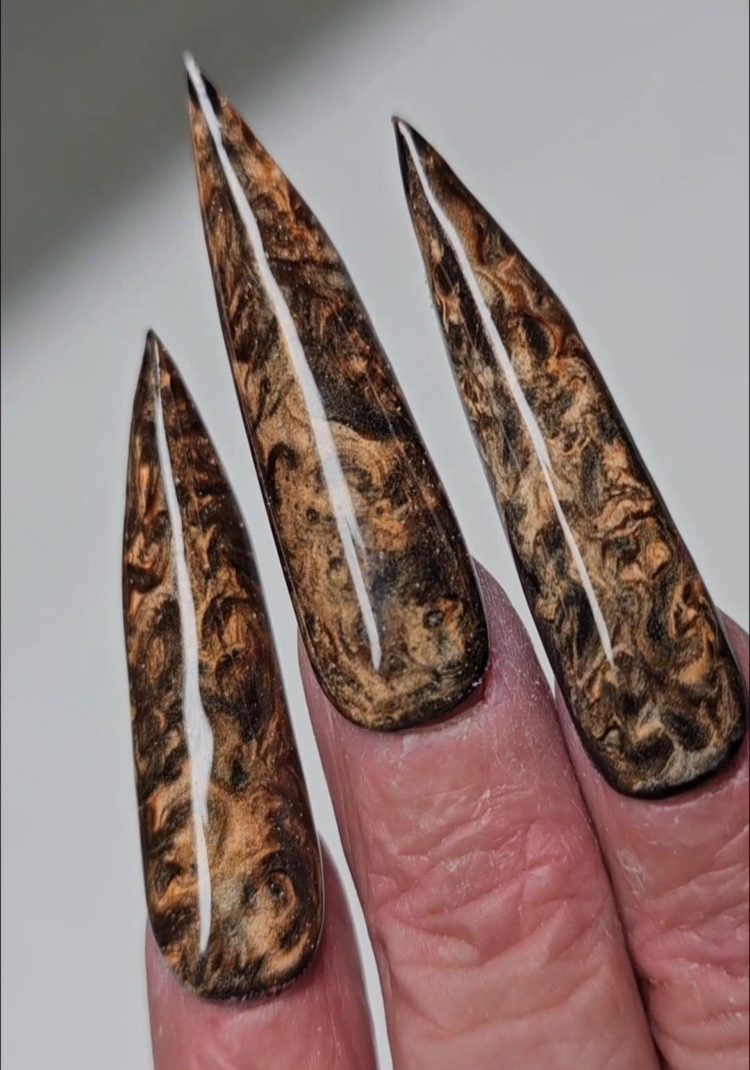 Cateye Twilight Kiss gellak - Detailopname van goudkleurig magnetisch cat-eye effect op zwarte basis - Luxe nail art op lange gothic almond nagels.