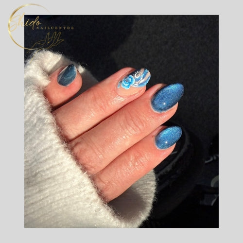 Blauwe cateye-nagels met magnetisch diepte-effect met helder blauwe glans. Luxe blauwe manicure met velvet finish. Op almond nagels met one stroke bloem op ringvinger.