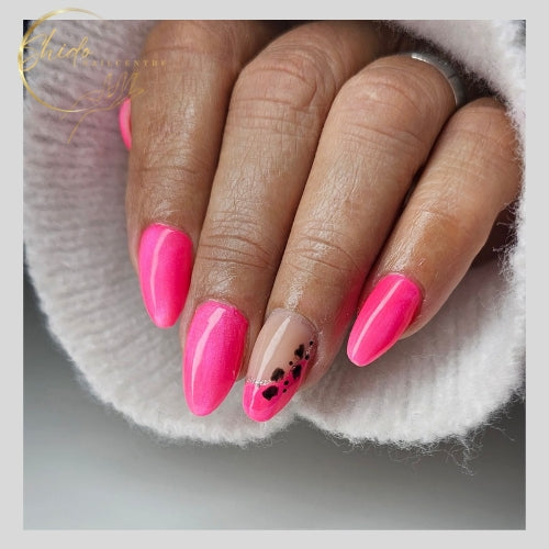Close-up van amandelvormige nagels gelakt met de felroze ShidoNails® Coco Cat Eye gellak, wat zorgt voor een dynamisch lichteffect. Één nagel heeft een accentnagel met een zwarte abstracte art op een nude basis. De hand ligt op een witte wollen ondergrond.
