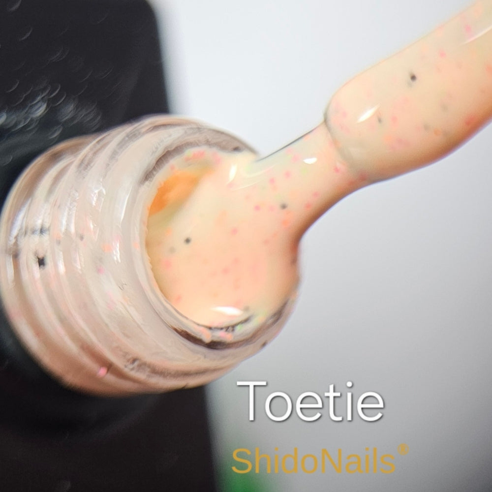 Macro-opname van ShidoNails gellak kleur Toetie, een zachte gele tint met vrolijke gekleurde spikkels en confetti-effect.