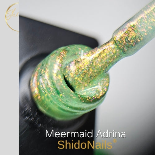 Detailopname van ShidoNails Meermind Adrina gellak op een applicatiekwastje met een frisse, transparante groen-gouden shimmer en iriserende deeltjes.